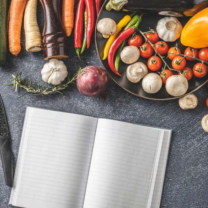 | Every Ingredient Open notebook on a kitchen counter surrounded by colorful spices, symbolizing cooking and recipe creation
